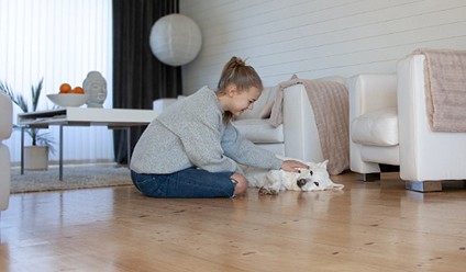 Tjej som sitter med en hund å ett golv.